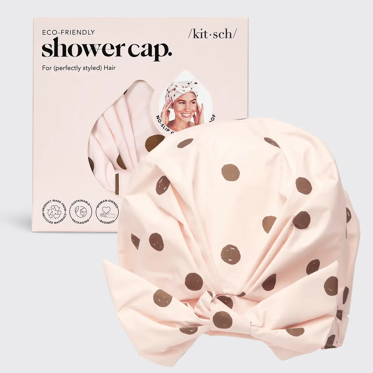 Pink shower cap with brown polka dots and packaging on a light gray background