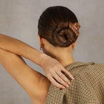 Woman with a stylish hair bun wearing a checkered dress against a neutral background