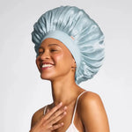 Woman wearing a light blue satin bonnet on a plain background