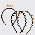 Set of tortoiseshell plastic headbands with kit-sch packaging on a light gray background
