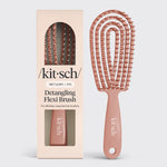 A Kitsch Detangling Flexi Brush shown next to its retail box. The brush has a dusty rose handle and flexible bristles, while the packaging is a pale peach-beige color with white branding.