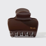 Brown hair clip with 'kit-sch' branding on a white background from Nespoli Jewelers.