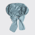 Light blue satin bonnet with a bow on a light gray background