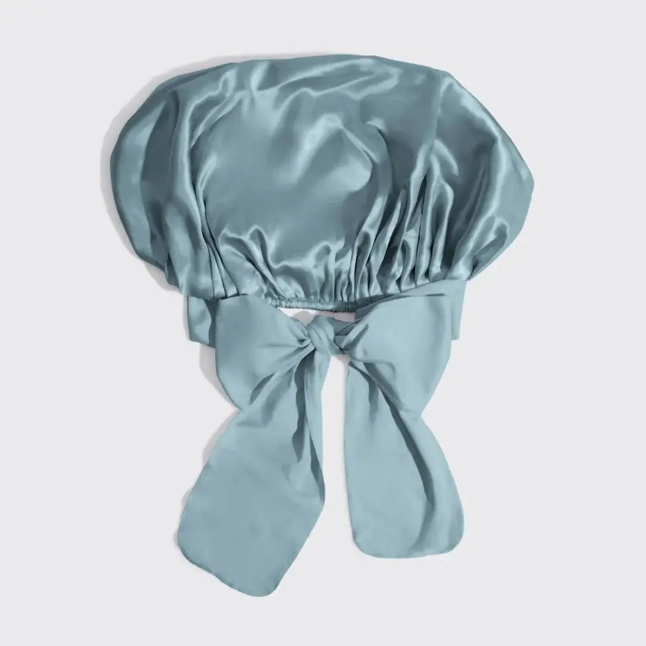 Light blue satin bonnet with a bow on a light gray background