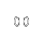 Silver huggie hoop earrings with small engraved details on a white background.