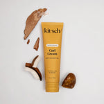 Kitsch Moisturizing Curl Cream tube with coconut pieces on a light gray background