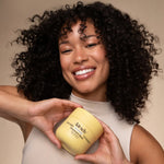 Woman holding a jar of Kitsch's hair mask against a beige background