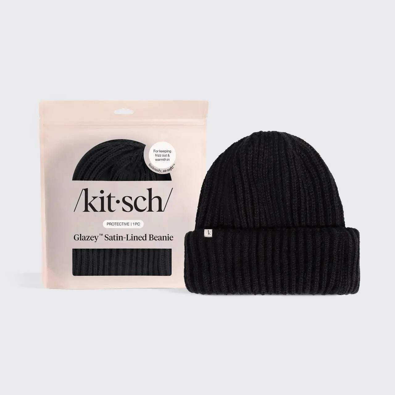 A black ribbed knit beanie hat displayed next to its light pink packaging pouch. The packaging features the brand name 'kit-sch' and the text 'Glazey Satin-Lined Beanie'.