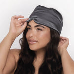 Woman wearing a gray satin Kitsch Satin Pillow Eye Mask against a white background