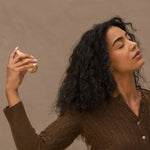 Woman holding Kitsch Rustic Vanilla perfume  against a brown background