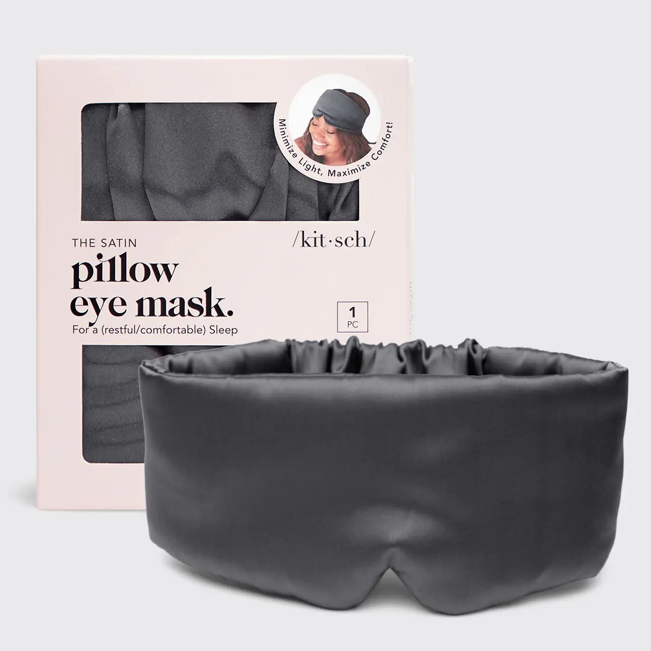 A dark gray satin pillow eye mask displayed in front of its light pink packaging box. The box features a window showing the matching dark gray mask inside and includes branding for 'kit·sch'.
