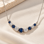 Zeghani 14K white gold necklace with alternating blue sapphires and diamonds displayed on soft ivory fabric.