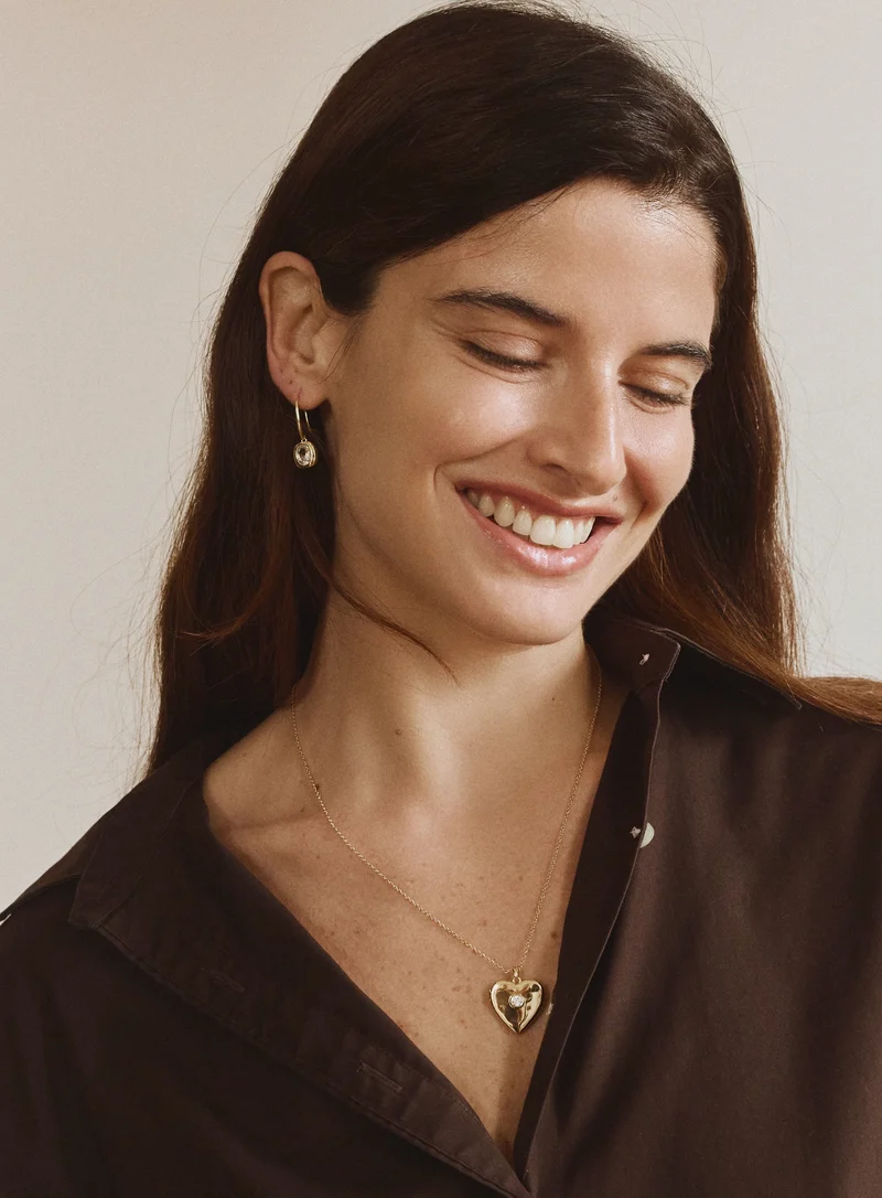 Woman wearing FYB gold dangle earrings with clear CZ stones