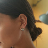 Woman wearing FYB silver rounded hoop earrings with a polished sculpted design