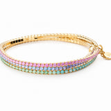 A gold-plated multi-strand bangle bracelet featuring rows of small iridescent rhinestones in pink, purple, and light blue, displayed on a clean white background.
