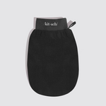 A black silicone hand scrubber mitt with a gray elastic wrist strap featuring the white printed brand name '/kit·sch/' and a small black pull tab, shown on a light gray background.