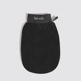 A black silicone hand scrubber mitt with a gray elastic wrist strap featuring the white printed brand name '/kit·sch/' and a small black pull tab, shown on a light gray background.