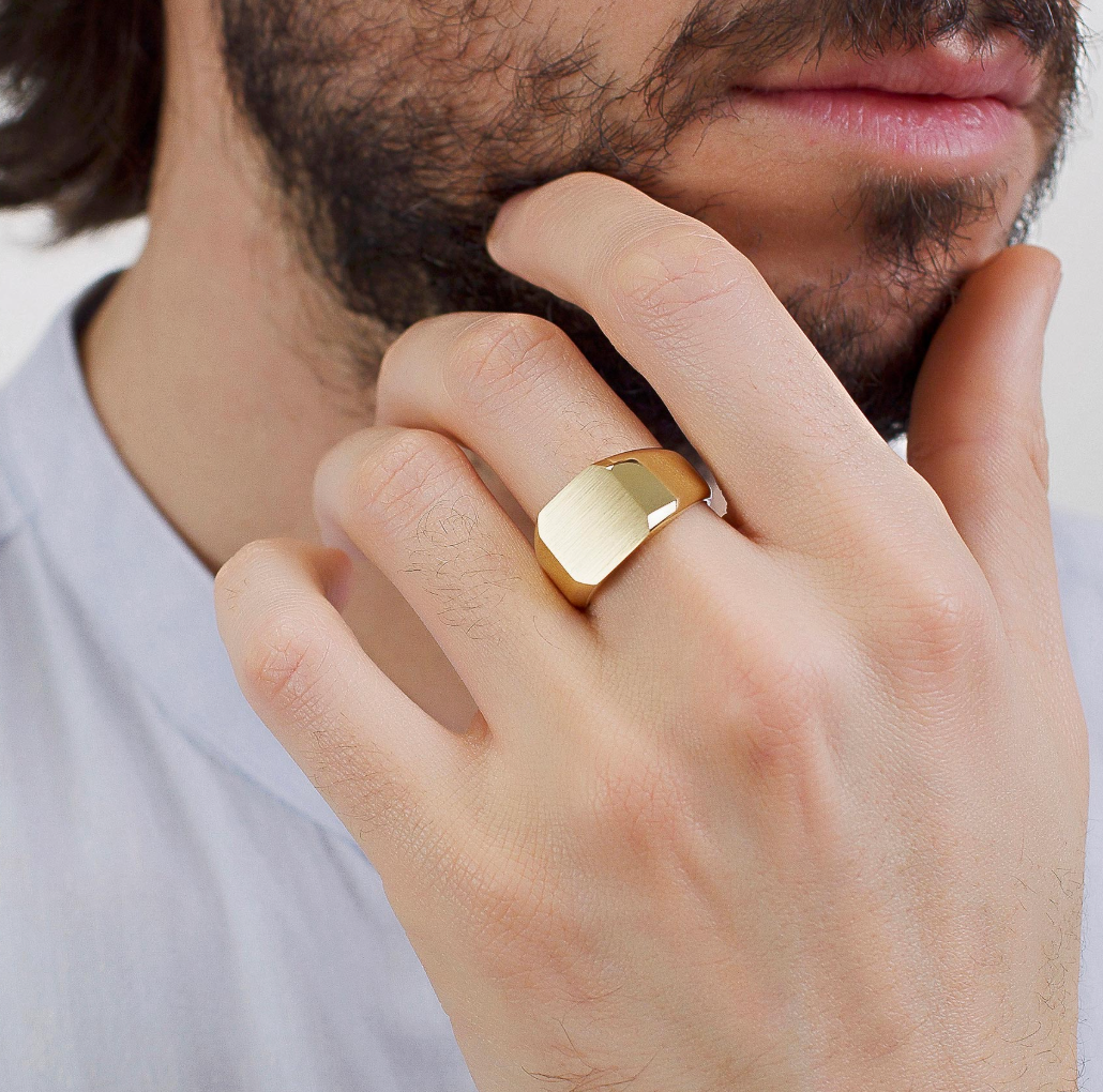 Man wearing a Brosway INK gold signet ring with a brushed geometric face and polished gold finish.