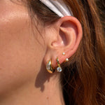 Woman wearing FYB gold hoop earrings with clear CZ accents in a layered earring look