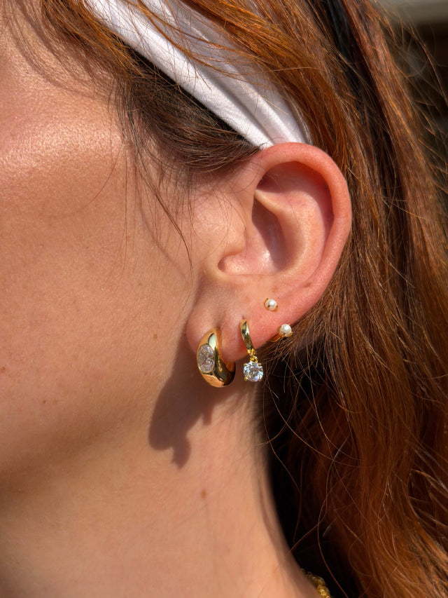 Woman wearing FYB gold hoop earrings with clear CZ accents in a layered earring look