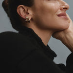Woman wearing gold FYB double CZ dangle earrings as part of a layered earring look.