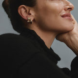 Woman wearing gold FYB double CZ dangle earrings as part of a layered earring look.