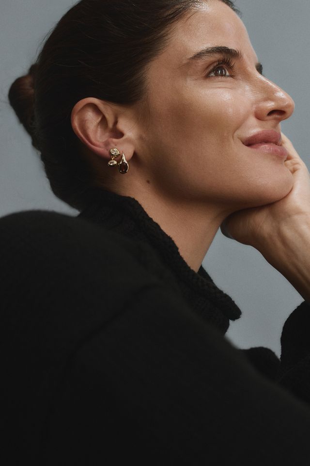 Woman wearing gold FYB double CZ dangle earrings as part of a layered earring look.