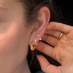 Woman wearing gold FYB double CZ stud earrings as part of a layered ear stack.