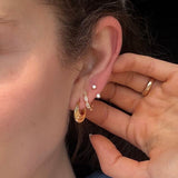 Woman wearing gold FYB double CZ stud earrings as part of a layered ear stack.