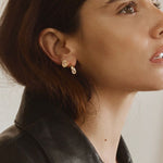 Woman wearing FYB gold stud earrings with clear CZ stones in a layered earring look