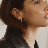 Woman wearing FYB gold stud earrings with clear CZ stones in a layered earring look