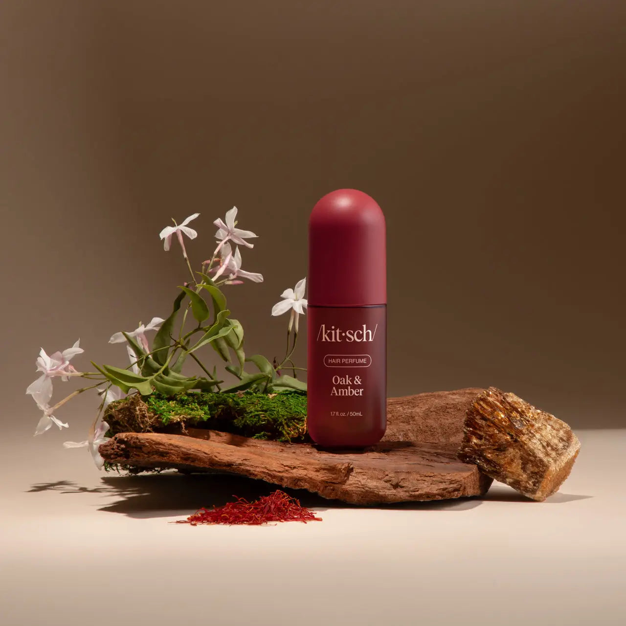 Kit-sch bottle of Oak & Amber on a wooden platform with flowers and natural elements.