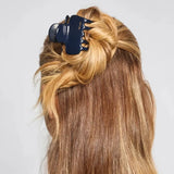 Blue hair clip in a person's blonde hair on a white background