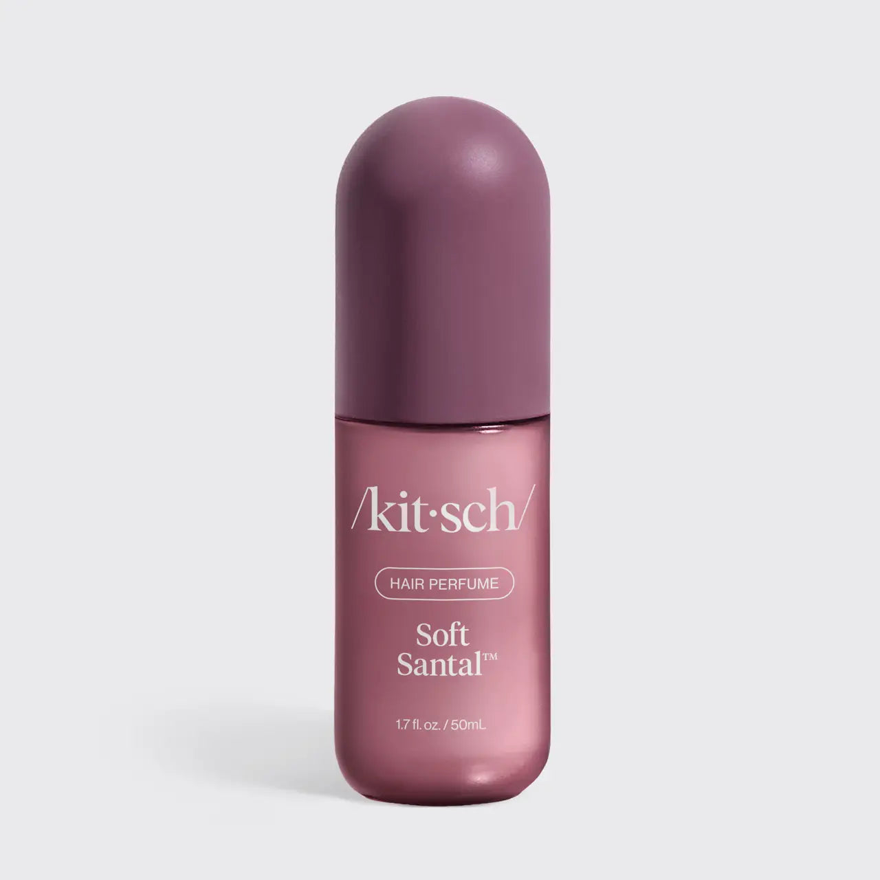 A bottle of kit-sch Soft Santal hair perfume, featuring a dusty purple cap and a metallic mauve-pink bottle with white text, set against a light gray background.