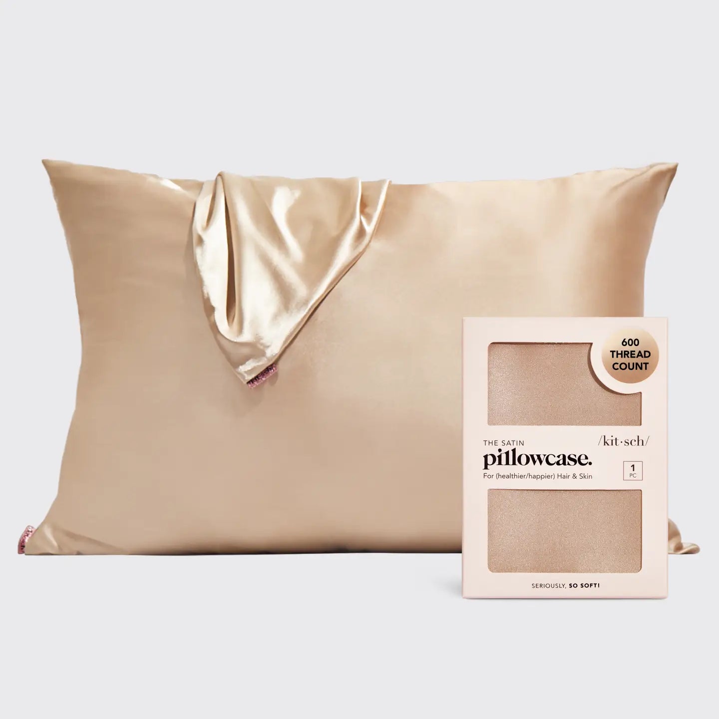 A champagne gold satin pillowcase with a matching satin tie-back corner, shown next to its light pink packaging box labeled 'kit:sch pillowcase' on a light gray background.