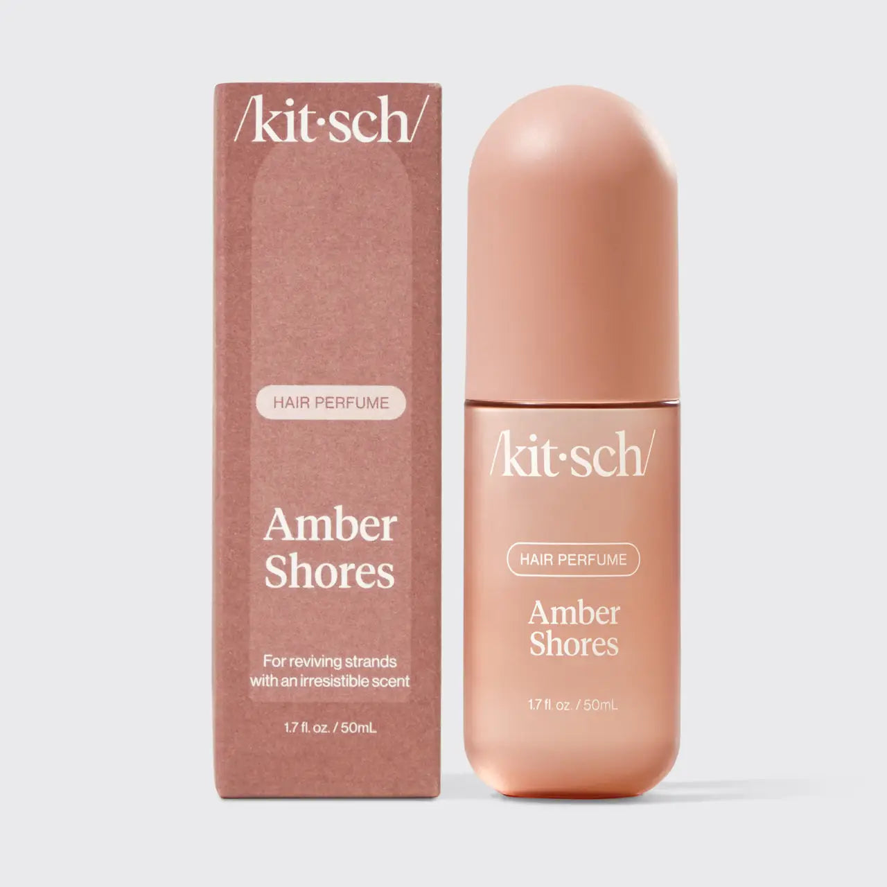 Kit Sch. Amber Shores hair perfume bottle and its matching packaging box, both in a warm peachy pink color, set against a light gray background.