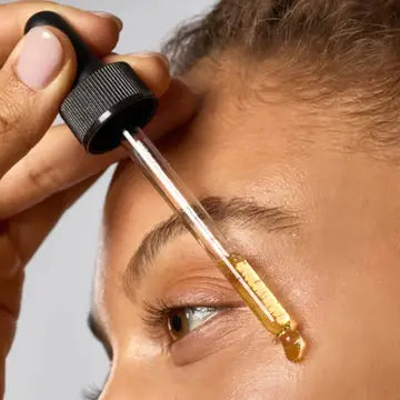 Close-up of a person applying a dropper of liquid to their eye.