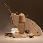 Kit-sch Rustic Vanilla perfume bottle with vanilla beans and flowers on a stone surface.