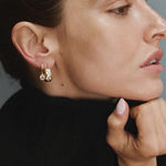 Woman wearing gold FYB cushion CZ dangle earrings with a layered earring look.