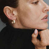 Woman wearing gold FYB cushion CZ dangle earrings with a layered earring look.