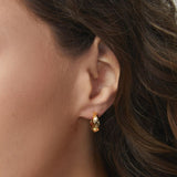 Woman wearing gold FYB twisted huggie hoop earrings for a close-up lifestyle view.