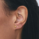 Woman wearing gold three-bead cluster stud earrings as part of a minimalist ear stack.